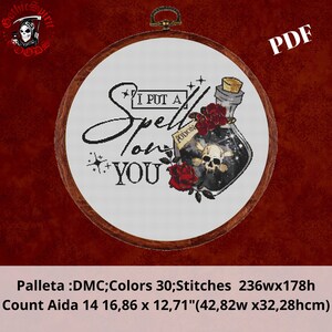 Puede incluir: Un patrón de punto de cruz con una botella de poción con una calavera y huesos cruzados, rosas rojas y el texto "I put a spell on you". El patrón está en un aro de bordado de madera y mide 42,82 cm por 32,28 cm.