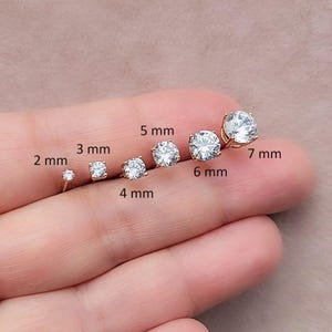 May include: A set of 7 gold stud earrings with clear round cubic zirconia stones. The stones are shown in different sizes, ranging from 2 mm to 7 mm.