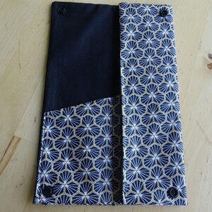 May include: Black and white fabric clutch with a geometric pattern and gold accents. The clutch has two snap closures.
