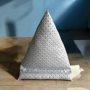 Peut inclure: Un coussin triangulaire gris et blanc avec un motif géométrique rose et noir. Le coussin est en tissu et a une texture douce et confortable.
