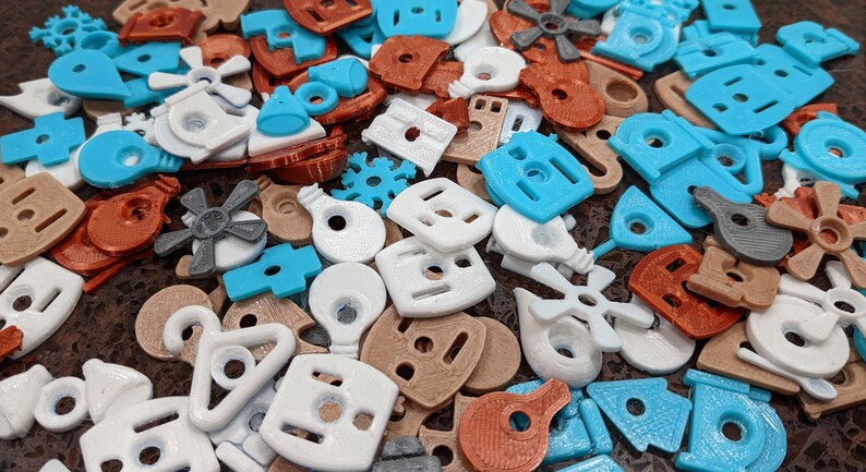 Puede incluir: Una colecci&oacute;n de formas de pl&aacute;stico de colores, incluyendo estrellas, casas y bombillas. Las formas son de varios colores, incluyendo azul, blanco, marr&oacute;n y naranja.