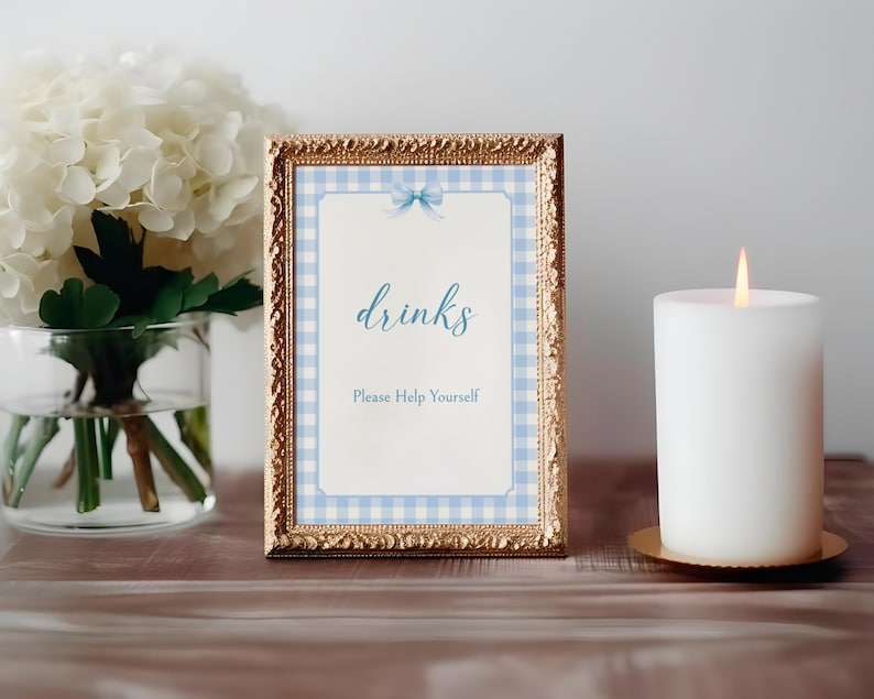 May include: A gold framed sign with a blue and white gingham pattern and a blue bow. The sign says "drinks" and "Please Help Yourself".