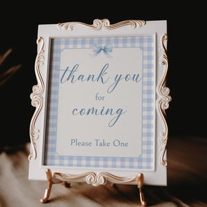 May include: White sign with a gold frame and a blue and white gingham pattern. The sign says "Thank you for coming. Please take one."