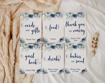 May include: Six printable signs with blue floral designs and white text. The signs say "cards and gifts", "food", "thank you for coming", "guest book", "drinks", and "babies are sweet".