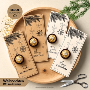 May include: Four rectangular paper cards featuring black line art of pine branches and snowflakes hanging like ornaments. Each card holds a single gold-wrapped Ferrero Rocher chocolate. Two cards are tan, two are cream, with Merry Christmas or Frohe Weihnachten text.