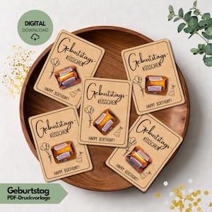 Könnte beinhalten: Sechs rechteckige Karten mit den Worten "Geburtstags-Küssen" und "Happy Birthday!" liegen in einer Holzschale. Jede Karte zeigt ein verpacktes Schokoladenbonbon. Die Karten sind beige mit schwarzem Text und Illustrationen.