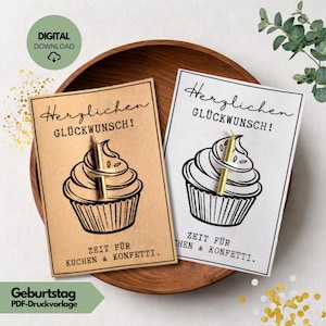 Puede incluir: Dos tarjetas con ilustraciones de cupcakes y alfileres dorados con forma de vela. Las tarjetas dicen "Herzlichen Glückwunsch!" y "Zeit für Kuchen & Konfetti." Una tarjeta es marrón, la otra blanca. Un cuenco de madera y vegetación en el fondo.