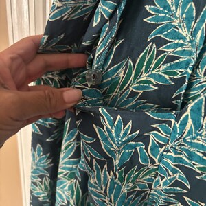 Puede incluir: Un vestido de estampado floral azul y verde con cierre de bot&oacute;n. El vestido tiene un bolsillo en el lado izquierdo.