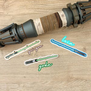 May include: Four colourful lightsaber stickers with the names "Qui-Gon", "Yoda", "Leia", and "Obi-Wan" written in cursive.