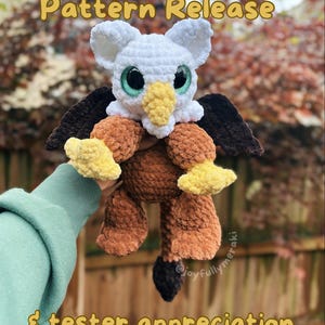 Può includere: Peluche di grifone fatto a mano all'uncinetto, con testa bianca, grandi occhi verdi e becco giallo. Il peluche ha accenti marroni e gialli, con ali marrone scuro. Il testo "Pattern Release" e "& tester appreciation" sono visibili.