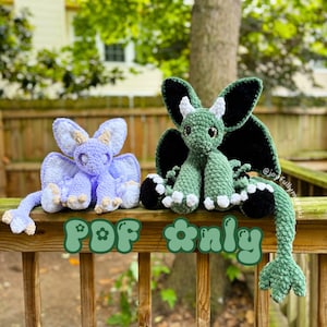 May include: Two handmade crochet dragons. One is light purple with tan accents, the other is green with black wings and white accents. The dragons are sitting on a wooden railing. Text on the railing reads "PDF only".