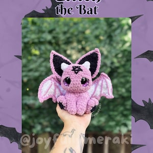 May include: A handcrafted crochet bat toy, named "Lilith", in shades of pink, black, and white. The bat has large eyes and detailed wings. The image features the text "Lilith the Bat" and social media handles.
