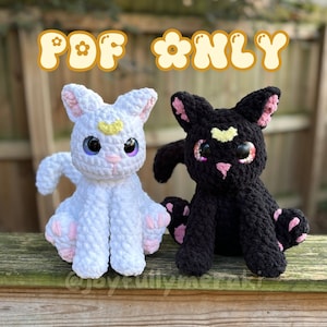 May include: Two crocheted cat plushies, one white with a yellow crescent moon and the other black with a yellow star, both with pink paws and large glittery eyes. The text "PDF *ONLY*" is displayed above the plushies.