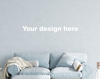 May include: A light blue sofa with a white throw blanket, a patterned pillow, and a white cylindrical pillow. The sofa is in front of a light blue wall with the text "Your design here". There are two white end tables with a wooden box on one of them.