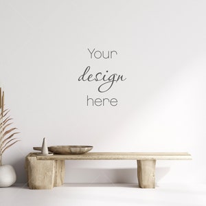 Pu&ograve; includere: Una panca di legno con una finitura naturale si trova di fronte a un muro bianco. Un vaso con una palma secca e un piccolo vaso di ceramica bianca sono sulla panca. Il testo "Your design here" &egrave; scritto sul muro.