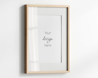 May include: A light wood picture frame with a white mat and a white background. The text "Your design here" is written in black cursive.