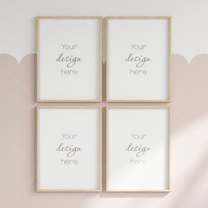 May include: Four empty picture frames with a light wood finish are hanging on a pale pink wall with a white ceiling. The frames are arranged in a square shape. The text "Your design here" is written in each frame.