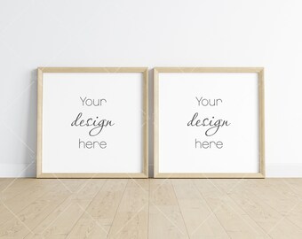 Puede incluir: Dos marcos de fotos de madera con paspartús blancos y el texto "Your design here" en cada marco. Los marcos están colgados en una pared blanca sobre un suelo de madera clara.
