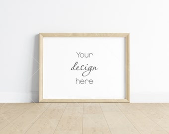 May include: A light wood picture frame with a white mat and the text "Your design here" inside the frame. The frame is sitting on a light wood floor in front of a white wall.