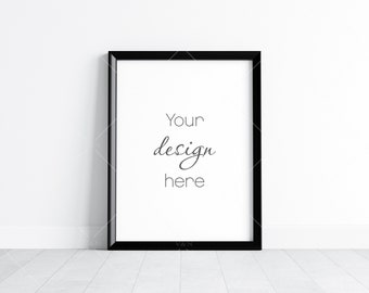 May include: A black picture frame with a white mat and the text "Your design here" inside the frame. The frame is sitting on a white wood floor in front of a white wall.