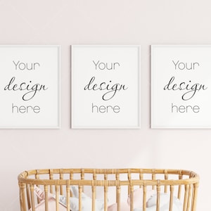 May include: Three white picture frames with the text "Your design here" in each frame, hanging on a pink wall above a wicker bassinet.