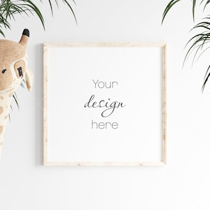 Könnte beinhalten: Ein weißer Bilderrahmen mit dem Text "Your design here" an einer weißen Wand mit einem Stofftier-Giraffe und einer grünen Pflanze auf jeder Seite des Rahmens.