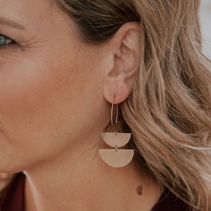 Puede incluir: Pendientes de tono dorado con dos formas de semicírculo apiladas.