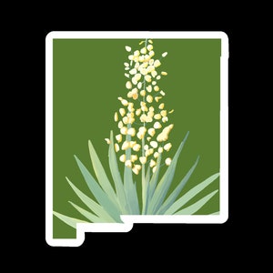 May include: A sticker featuring the outline of New Mexico with a green background. A white flower with yellow buds and long, light green leaves is in the center of the sticker. The sticker has a white border.