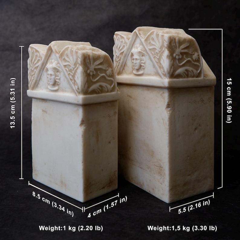 Puede incluir: Dos sujetalibros rectangulares de piedra color hueso con remates en front&oacute;n que presentan relieves de rostros humanos y motivos florales. El m&aacute;s peque&ntilde;o mide 13,5 cm de alto, 8,5 cm de ancho y 4 cm de fondo, pesando 1 kg. El m&aacute;s grande mide 15 cm de alto, 5,5 cm de fondo, pesando 1,5 kg.