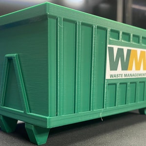 K&ouml;nnte beinhalten: Ein gr&uuml;ner Abfallcontainer mit dem Logo "WM Waste Management" an der Seite. Der Container steht auf R&auml;dern und hat eine Metallt&uuml;r an der R&uuml;ckseite.
