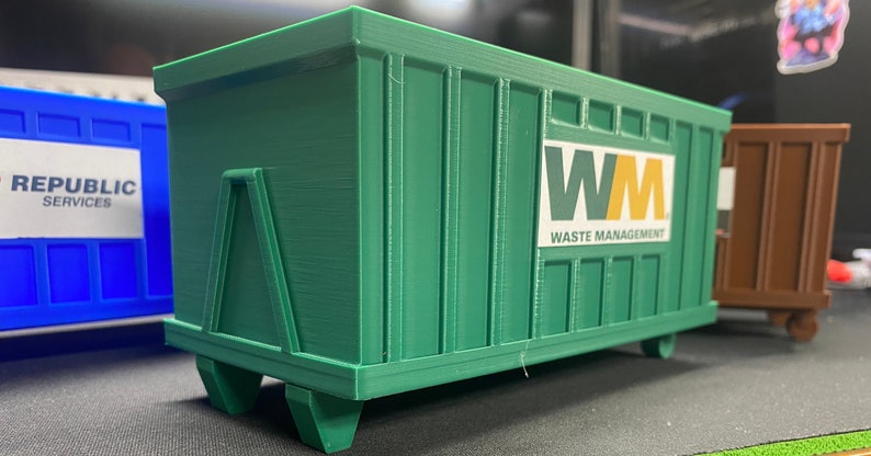 K&ouml;nnte beinhalten: Ein gr&uuml;ner Abfallcontainer mit dem Logo "WM Waste Management" an der Seite. Der Container steht auf R&auml;dern und hat eine Metallt&uuml;r an der R&uuml;ckseite.