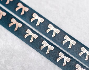 May include: Two navy blue ribbons with a repeating pattern of light pink and white bows. The bows are evenly spaced along the length of the ribbons. The ribbons are slightly angled.
