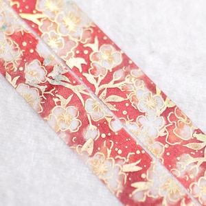 May include: Red washi tape with a gold floral pattern. The tape has a delicate design of white flowers and gold leaves on a red background.