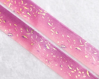 May include: Two rolls of pink and white washi tape with gold foil accents. The tape has a gradient design with a pink to white ombre effect. The gold foil accents are small and scattered throughout the tape.