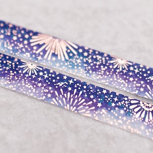 May include: Two rolls of washi tape with a blue and purple watercolour background and gold foil fireworks and stars.