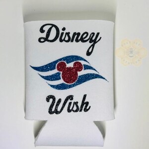 May include: White can cooler with the words "Disney Wish" in black script. The design includes a red glitter Mickey Mouse head and blue glitter waves. A small logo is visible in the upper right corner.