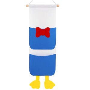 May include: A wall hanging organizer shaped like Donald Duck. The organizer features a white top, blue body with a red bow tie, and yellow feet. It is designed to hang from a wooden dowel.