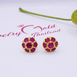 May include: A pair of gold stud earrings with a cluster of pink gemstones. The earrings are set against a white background.