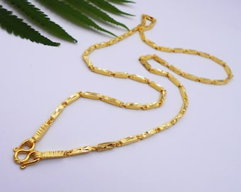 May include: A gold chain necklace with a diamond-shaped pattern. The chain is made of small, linked pieces that are all the same size and shape.