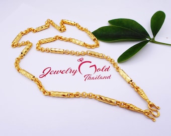 May include: A gold chain necklace with a textured, rectangular link design. The chain has a clasp with a decorative design.