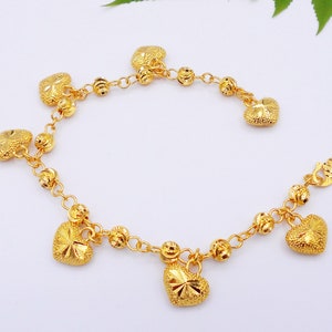 May include: A gold-tone bracelet with a chain link design and multiple heart-shaped charms. The bracelet has a lobster claw clasp.