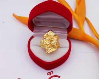 May include: A gold flower ring with intricate details, displayed in a red velvet ring box.