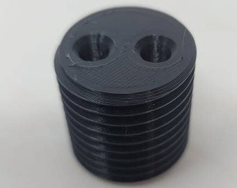 May include: A black 3D printed object with two holes on the top and a ribbed design.