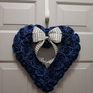 K&ouml;nnte beinhalten: Ein herzf&ouml;rmiger Kranz aus dunkelblauen Stoffrosen mit einer wei&szlig;en und grauen Gingham-Schleife.