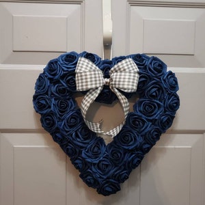 K&ouml;nnte beinhalten: Ein herzf&ouml;rmiger Kranz aus blauen Stoffrosen mit einer wei&szlig;en und grauen Gingham-Schleife.
