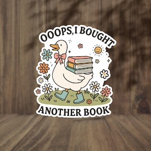 May include: A sticker featuring a cartoon goose carrying a stack of books. The goose wears a pink bow and blue boots, surrounded by flowers and the text "OOOPS, I BOUGHT ANOTHER BOOK". A smiling sun is also present.