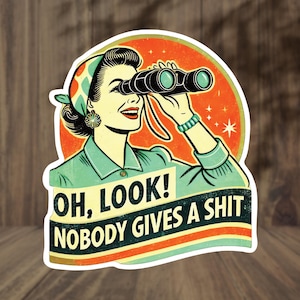 May include: A retro-style sticker featuring a woman looking through binoculars. The image has a vintage aesthetic with a color palette of teal, orange, and beige. Text on the sticker reads "OH, LOOK! NOBODY GIVES A SHIT."