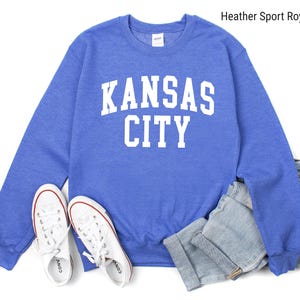 May include: A heather sport royal blue sweatshirt with white text that reads "Kansas City".