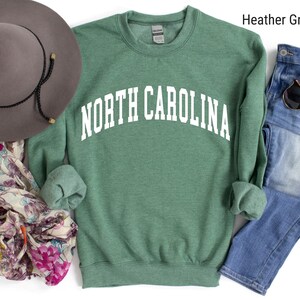 Pode incluir: Camisola de moletom verde com o texto "NORTH CAROLINA" em branco.