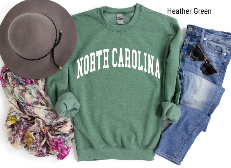 Pode incluir: Camisola de moletom verde com o texto "NORTH CAROLINA" em branco.